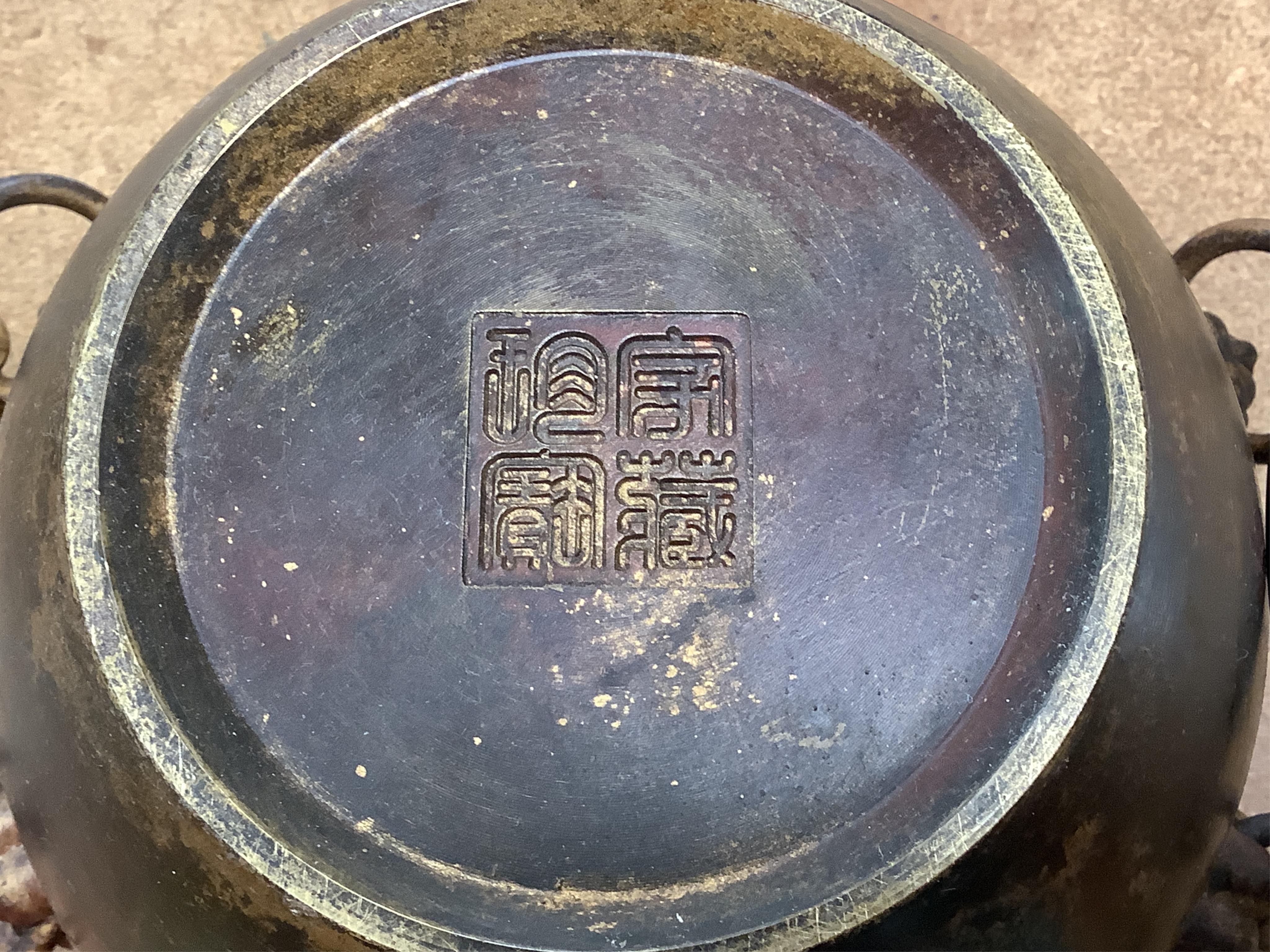A Chinese partially gilt bronze censer, decorated in relief with twin handles, 16cm in diameter